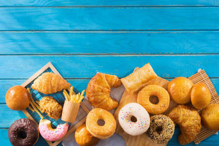 assorted junk food multiple type on blue wooden table of top view with copy space.の写真素材