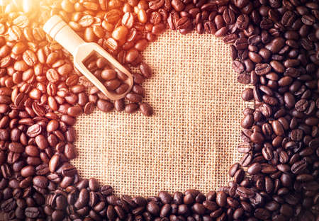 Scoop on coffee beans arranged as a heart shape on bag background.の写真素材