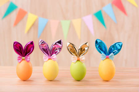 Happy Easter day colorful eggs with bunny ears on wooden floor blurred celebrate banner party flags with copy space.の写真素材