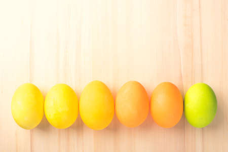 Happy Easter with colorful eggs on brown wooden floor top view with copy space.の写真素材