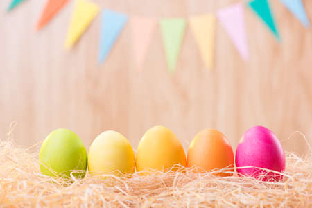 Happy Easter day colorful eggs on nest with blurred celebrate banner party flags with copy space.の写真素材