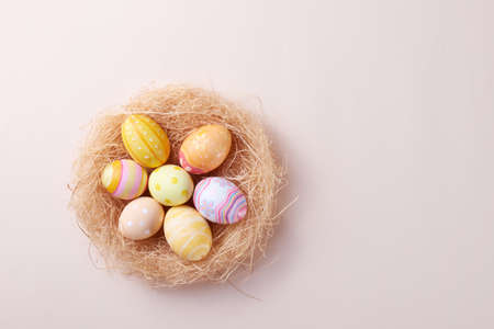 Happy Easter day colorful eggs in nest on paper background with copy space.
