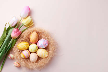 Happy Easter day colorful eggs in nest and flower on paper background with copy space.