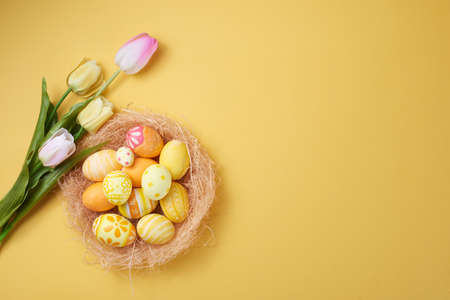 Happy Easter day colorful eggs in nest and flower on paper background with copy space.