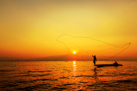 throwing fishing net during sunsetの写真素材