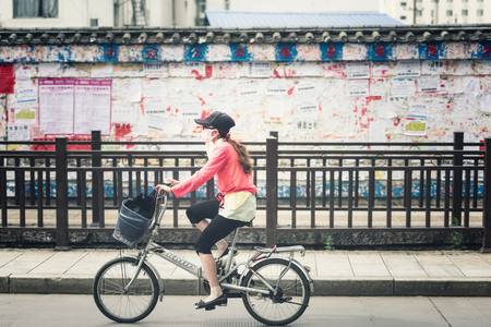 Lijiang, China - Jun 21, 2015: : Woman riding a bicycle in Lijiang ancient town in China on Jun 21, 2015, Lijiang is one of the most beautiful cities of China with a rich culture and history.のeditorial素材