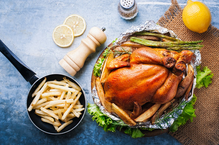 Whole roasted chicken with vegetables on wood tableの写真素材