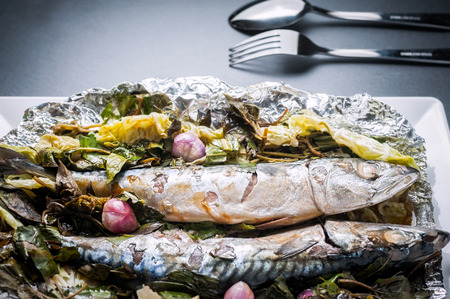 Steamed Saba fish with soy sauce and vegetable in foil on white plateの写真素材
