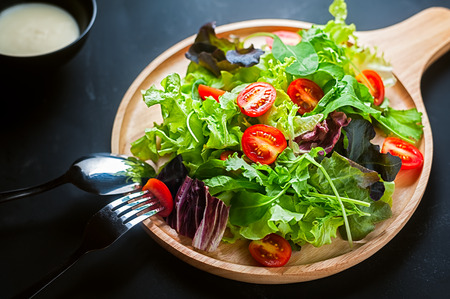Fresh mixed vegetables salad on a wooden plateの写真素材
