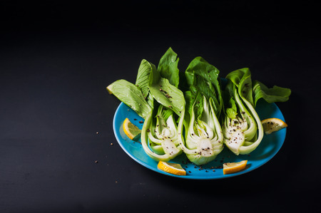 Fresh Chinese cabbage or Bok Choy with lemon slice and pepper on blue dishの写真素材