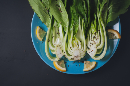 Fresh Chinese cabbage or Bok Choy with lemon slice and pepper on blue dishの写真素材