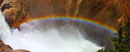 Sunlight creates a rainbow in mists of the Lower Falls of the Yellowstone River in Wyomingの写真素材