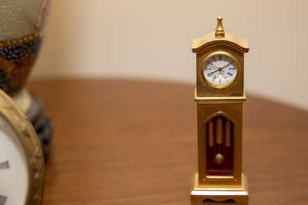 A selective focus shot of a decorative vintage clock on the wooden table