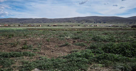 A field surrounded by high mountains gleaming under the cloudy sky