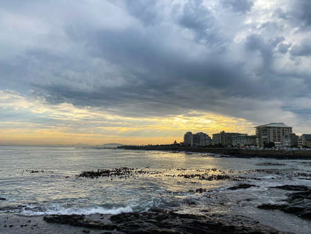 A beautiful view of a sea with buildings in the city under a cloudy skyの写真素材