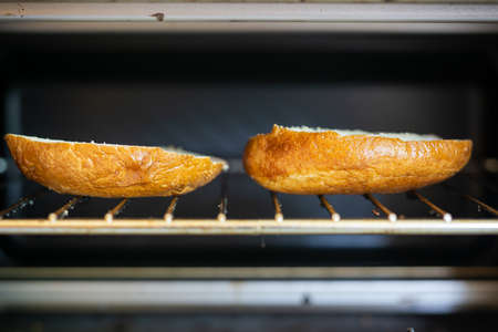 A selective focus shot of the two beagle slices inside of a toaster oven