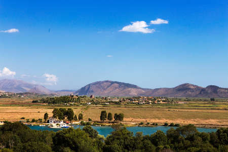 A landscape shot of a field next to a river under the blue skyの写真素材