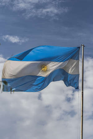 The flag of Argentina waving on the wind and some clouds in the sky on backgroundの写真素材