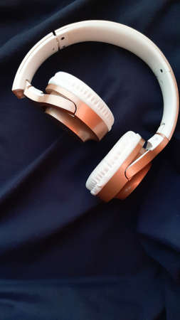 A vertical closeup shot of white headphones on blue backgroundの写真素材