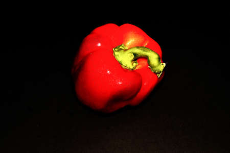 A close up shot of a red shiny pepper isolated on a black backgroundの写真素材