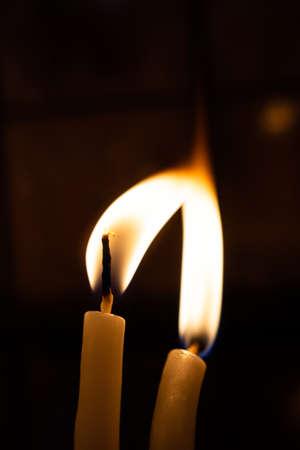 A vertical shot of two lit candles with a dark blurry background