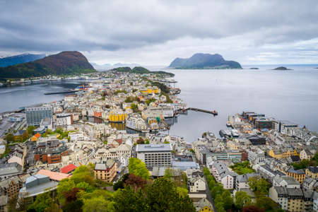 Skyline and cityscape of Alesund, Norway, on a cloudy day. Ocean bay in the background, bright houses and architecture in the foreground. Aerial view.の写真素材
