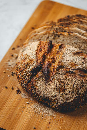 Close up view on freshly baked sourdough bread on wooden cutting board on bright backgroundの写真素材