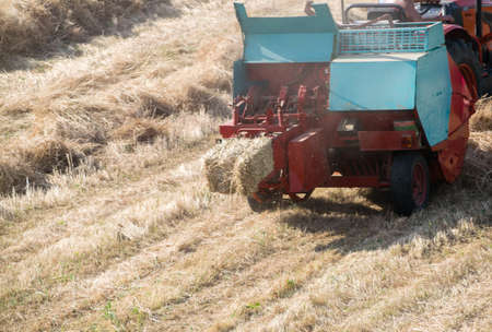 A high angle shot of a tractor collecting haystacks in a hayfieldの写真素材