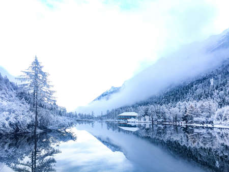 A beautiful shot of the reflection of snow-peaked mountains in the mist in Sichuan Province, China