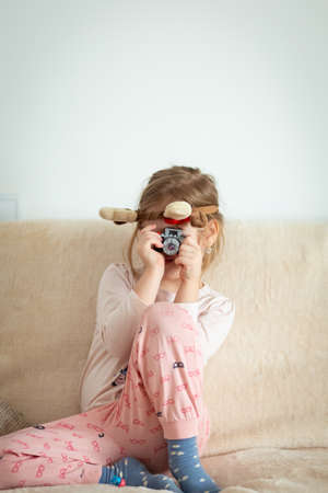 A vertical shot of little girl taking a photograph with a camera toyの写真素材