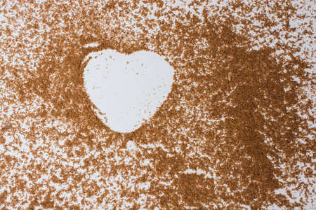 A closeup of a heart-shape drawn with brown powder on a table - great for romantic backgroundsの写真素材