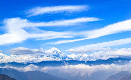 A mesmerizing shot of snow-peaked mountains in the clouds in Sichuan Province, Chinaの写真素材