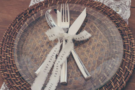 A high angle shot of a fork and a knife decorated with a white ribbon at a wedding partyの写真素材