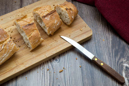 A high angle shot of a freshly-baked breast on a wooden cutting board with a knife