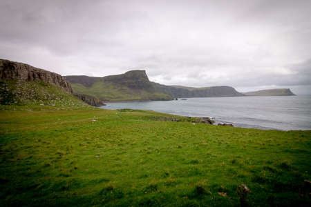 A beautiful view of the grass-covered cliffs by the ocean captured in Neist Point, Waterstein, UK