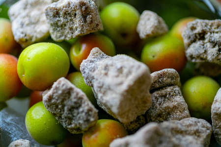 A close up shot of the umeshu Japanese plum wine making process with regular and brown sugar cubes