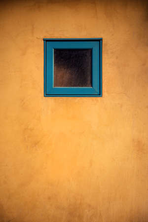 A vertical shot of a tiny blue window on a wooden doorの写真素材