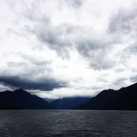 A beautiful scenery of white clouds over a peaceful sea surrounded by cliffs