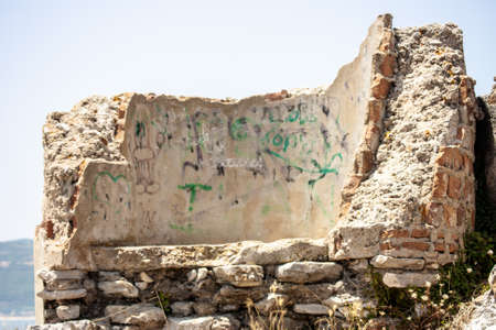 A selective focus shot of an old ruined wall with black and green writings on itの写真素材
