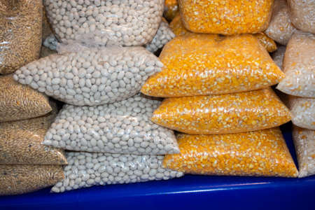 A closeup shot of corn and beans in plastic packages on a blue surfaceの写真素材