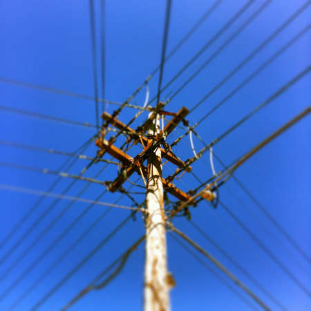 A low angle shot of a pole with electricity wires under a clear blue sky