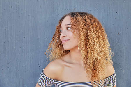 A closeup shot of a young beautiful Latin female with curly hair posing at camera