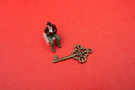 A high angle shot of a vintage key on orange background with a man figure