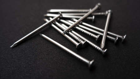 A closeup shot of some steel nails on a black surface