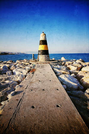A vertical shot of an old lighthouse at the end of a pier by the beautiful and calm ocean