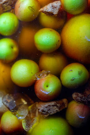 A close up shot of the umeshu Japanese plum wine making process with regular and brown sugar cubes