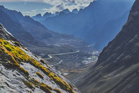 The high mountains with long winding roads gleaming under the cloudy sky