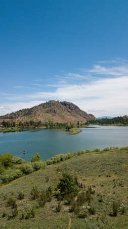 An aerial shot of a lake in a mountain landscape with green trees