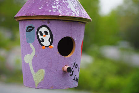 A closeup shot of a purple wooden birdhouse with blurred backgroundの写真素材