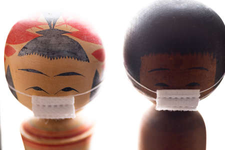 A shallow focus shot of wooden Asian dolls wearing medical masks during Covid-19 - the new normalの写真素材